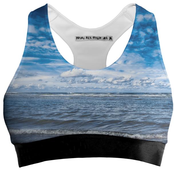 Cloudy day on the beach Sports Bra