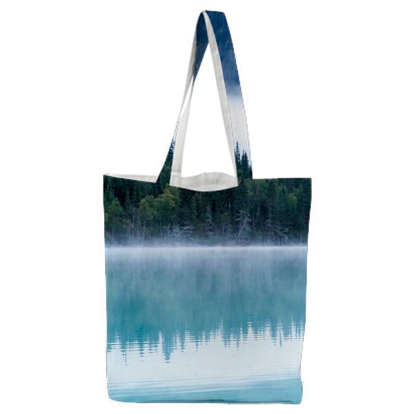 Green Trees Near Large Body Of Water Under Gray And White Sky During Daytime Tote Bag
