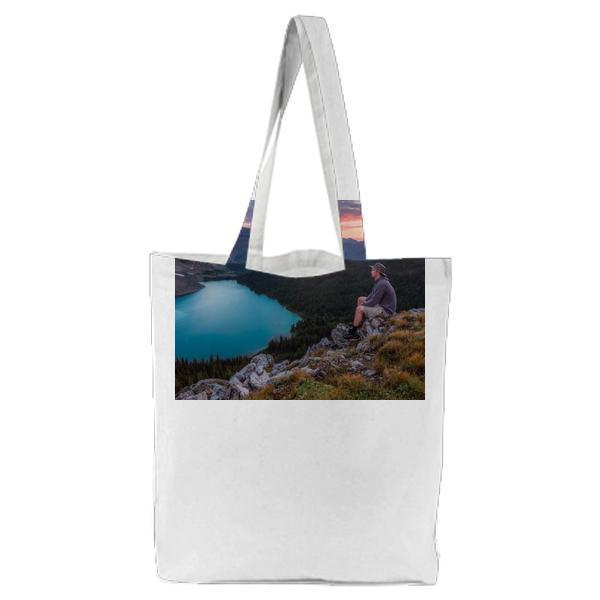 Person Sitting On Gray Rocks During Sunset Tote Bag