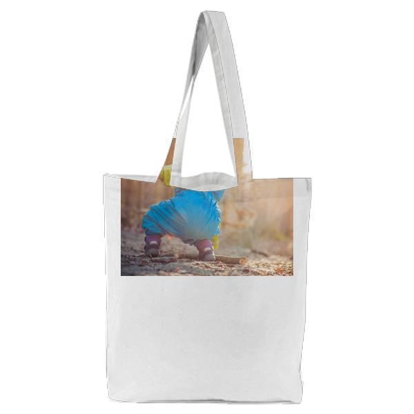 Baby Wearing Blue And Green Rain Coat Picking Brown Dead Tree Branch During Daytime Tote Bag