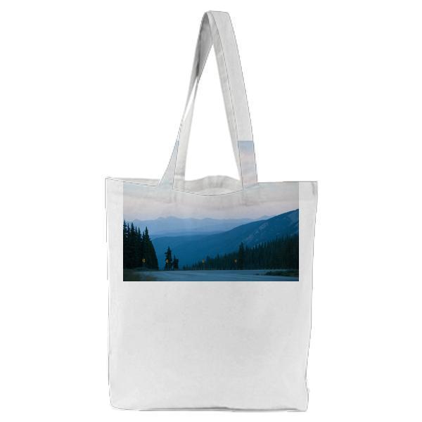 Gray Concrete Road Surrounded By Pine Trees Under Gray Sky Tote Bag