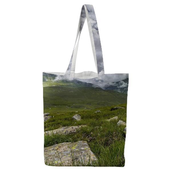 Green Grass Field With Rocks Near Mountains During Cloudy Daytime Sky Tote Bag