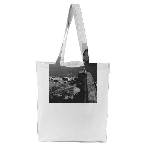 White And Black Tower Near The Sea Under White Sky Tote Bag