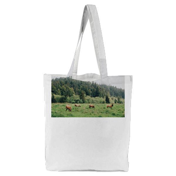 Pack Of Deer Eating On Plane Grass Field During Daytime Tote Bag