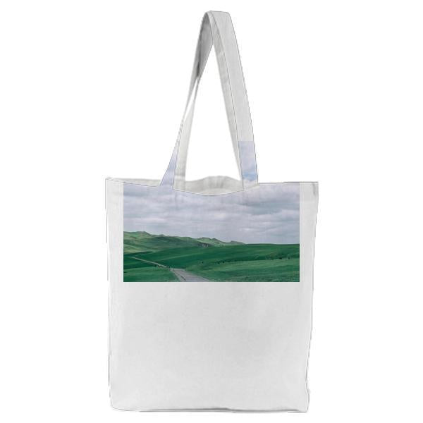 Green Grass Near Straight Road Under White Clouds And Blue Sky During Daytime Tote Bag