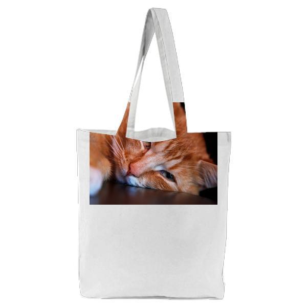 Orange Tabby Cat Leaning Head On Brown Surface Tote Bag