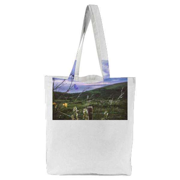 Blue And Yellow Flower On Grass Field Under Cloudy Sky During Daytime Tote Bag